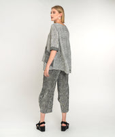 model in a wide leg black and white striped top with a flowy matching pullover top with contrasting pockets and sleeve cuffs