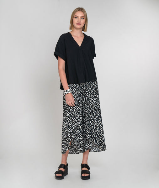 model in a wide leg black and white dot pant worn with a boxy black vneck top.