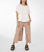 model in a white top with a khaki color pant with a draped side