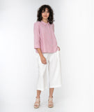 model in a cropped white pant with a red and white pinstripe button down top