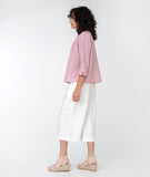 model in a cropped white pant with a red and white pinstripe button down top