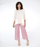 model in a white pullover top with a red and white pinstripe pant with asymmetrical pockets