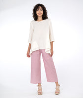 model in a white pullover top with a red and white pinstripe pant with asymmetrical pockets