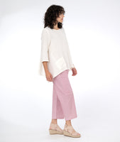 model in a white pullover top with a red and white pinstripe pant with asymmetrical pockets