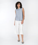 model in a cropped white pant with a blue and white pinstripe sleeveless button down top