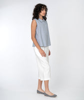 model in a cropped white pant with a blue and white pinstripe sleeveless button down top