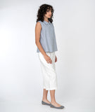 model in a cropped white pant with a blue and white pinstripe sleeveless button down top