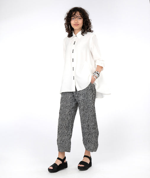 model in a black and white striped pant with a long, flowy white button down blouse