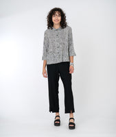 model in a black straight leg pant with a white and black striped button down top with elbow length sleeves