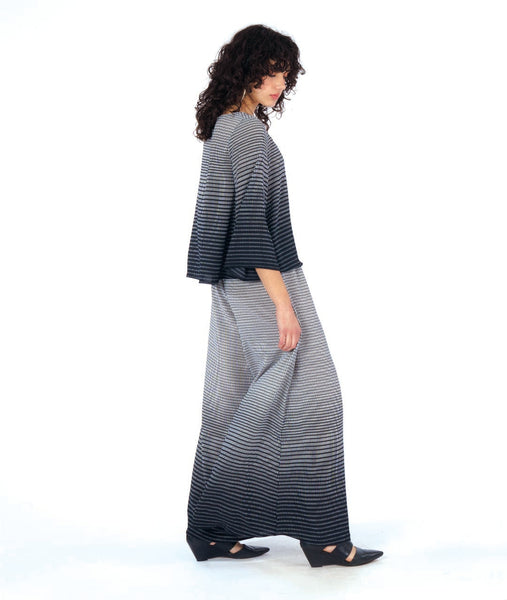 model in a ultra wide leg palazzo pant in a black and white grid ombre print, worn with a matching pullover top with a wide body and wide sleeves, giving a bell shape