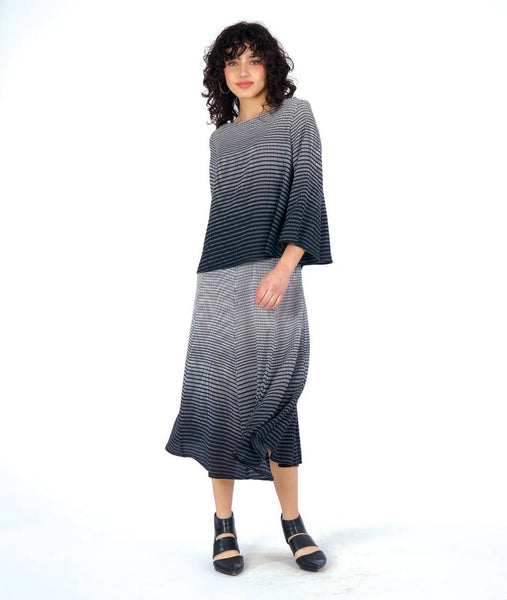 model in a paneled black and white grid ombre print midi length skirt, worn with a matching pullover top with a wide body and wide sleeves, giving a bell shape