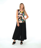 A woman modeling a sleeveless black top with a vibrant multicolor floral print, paired with wide-leg black pants and black slide sandals, against a solid white studio background.