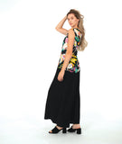 A woman modeling a sleeveless black top with a vibrant multicolor floral print, paired with wide-leg black pants and black slide sandals, against a solid white studio background.