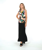 A woman modeling a sleeveless black top with a vibrant multicolor floral print, paired with wide-leg black pants and black slide sandals, against a solid white studio background.