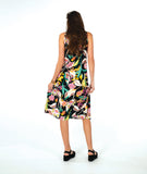 A woman modeling a sleeveless shift dress with a vibrant multicolor floral print on a black background, paired with black platform sandals, against a solid white studio background.