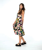 A woman modeling a sleeveless shift dress with a vibrant multicolor floral print on a black background, paired with black platform sandals, against a solid white studio background.