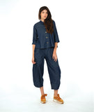 model wearing a dark wash chambray button down blouse with 3/4 sleeves and a twin button detail. worn with a matching barrel leg pant with oversized pockets and a yellow shoe