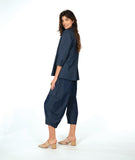 model in a dark wash chambray jacket with a small split at the waist seam. Jack has 3/4 sleeves and sits open. Worn with a matching barrel leg pant
