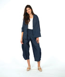 model in a dark wash chambray jacket with a small split at the waist seam. Jack has 3/4 sleeves and sits open. Worn with a matching barrel leg pant