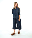 model in a dark wash chambray button down blouse with a princess seam and dolman sleeve. worn with a matching wide leg pant with brown loafers