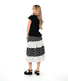 A woman modeling a black short-sleeve top with a black and white tiered polkadot skirt. top has a v-neck, peplum and fluttery sleeves