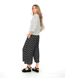 model in a wide leg black cropped pant with white dots, worn with a white pullover top with a cowl neck and black dots