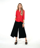 A woman modeling a bright red button-up blouse with three-quarter sleeves and black wide-leg pants,with an overlapping front 