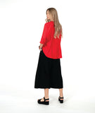 A woman modeling a bright red button-up blouse with three-quarter sleeves and black wide-leg pants,with an overlapping front 