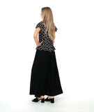 A woman modeling a black short-sleeve top with white polka dots and a long wide leg black pant. top has a v-neck, peplum and fluttery sleeves