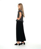 A woman modeling a black short-sleeve top with white polka dots and a long wide leg black pant. top has a v-neck, peplum and fluttery sleeves