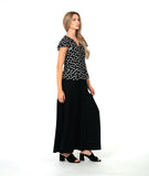A woman modeling a black short-sleeve top with white polka dots and a long wide leg black pant. top has a v-neck, peplum and fluttery sleeves