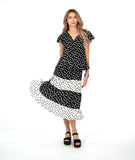 A woman modeling a black dot short-sleeve top with a black and white tiered polkadot skirt. top has a v-neck, peplum and fluttery sleeves