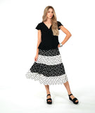 A woman modeling a black short-sleeve top with a black and white tiered polkadot skirt. top has a v-neck, peplum and fluttery sleeves