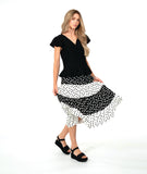 A woman modeling a black short-sleeve top with a black and white tiered polkadot skirt. top has a v-neck, peplum and fluttery sleeves