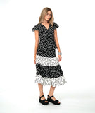 A woman modeling a black dot short-sleeve top with a black and white tiered polkadot skirt. top has a v-neck, peplum and fluttery sleeves