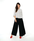 model in a black wide leg pant with a white button up blouse with black dots