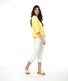 model in a white cropped pant with an acid yellow button up blouse