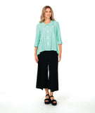 model in a wide leg black pant with a drapey mint green button down blouse