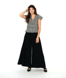 model in a wide leg black pant with and over lapping front panel. worn with a black and white stripe pullover top with a flutter peplum and sleeves, and a v neck with contrasting stripe panels 