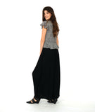 model in a wide leg black pant with and over lapping front panel. worn with a black and white stripe pullover top with a flutter peplum and sleeves, and a v neck with contrasting stripe panels 