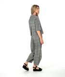 model in a black and white striped barrel leg pant with a matching button down blouse with 3/4 sleeves and a double button detail