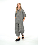 model in a black and white striped barrel leg pant with a matching button down blouse with 3/4 sleeves and a double button detail