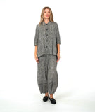 model in a black and white stripe wide leg pant with a mid calf tuck detail. worn with a matching blouse with 3/4 sleeves, a flowy body, and oversized pockets