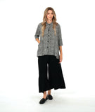 model in a wide leg pant with overlapping front panels, worn with a black and white button down blouse with 3/4 sleeves, a full body, and oversized contrast stripe pockets