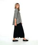 model in a wide leg pant with overlapping front panels, worn with a black and white button down blouse with 3/4 sleeves, a full body, and oversized contrast stripe pockets