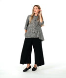 model in a wide leg pant with overlapping front panels, worn with a black and white button down blouse with 3/4 sleeves, a full body, and oversized contrast stripe pockets