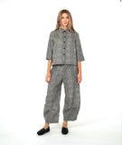 model in a black and white striped barrel leg pant with a mid calf tuck detail. worn with a matching blouse with a contrasting stripe placket and cuff