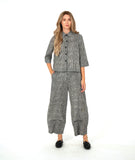 model in a black and white striped barrel leg pant with a mid calf tuck detail. worn with a matching blouse with a contrasting stripe placket and cuff