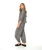 model in a black and white striped barrel leg pant with a mid calf tuck detail. worn with a matching blouse with a contrasting stripe placket and cuff