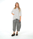 model in a barrel leg stripe pant with a white button down with black dots